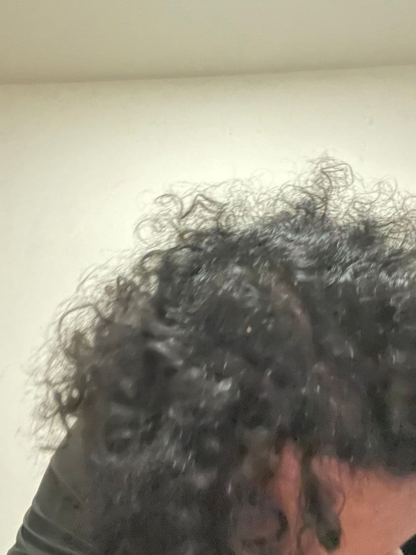 Fingers parting thick curls to expose the scalp