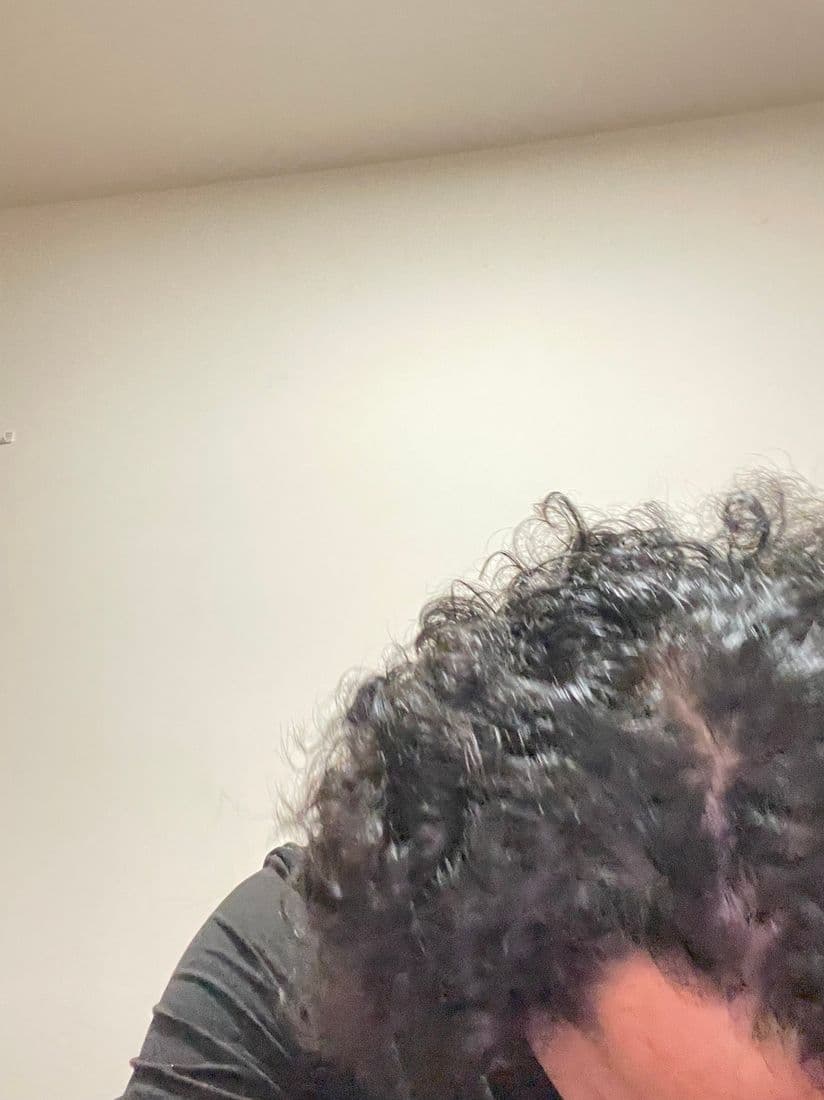 Hand working serum into the hair at the crown